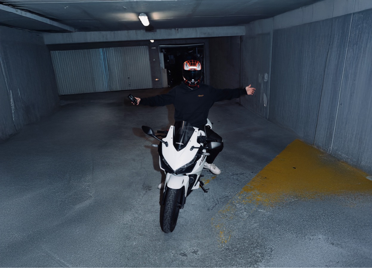 Vidéaste casqué à moto dans un parking, camera au poing