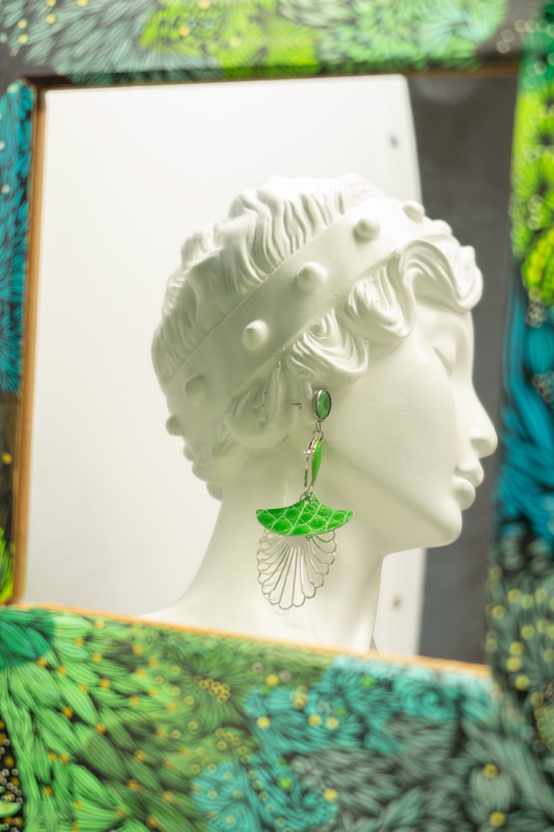 Boucle d'oreille verte sur buste, fond coloré